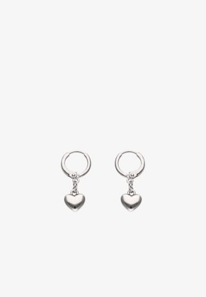 Małe srebrne kolczyki-koła z gładkimi zawieszkami w kształcie serca zwisającymi z każdego koła, przedstawione na białym tle.