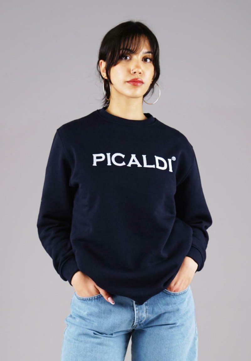 Navy blue sweatshirt with "PICALDI" logo in white, crew neck, long sleeves, and ribbed cuffs. Paired with light blue jeans.