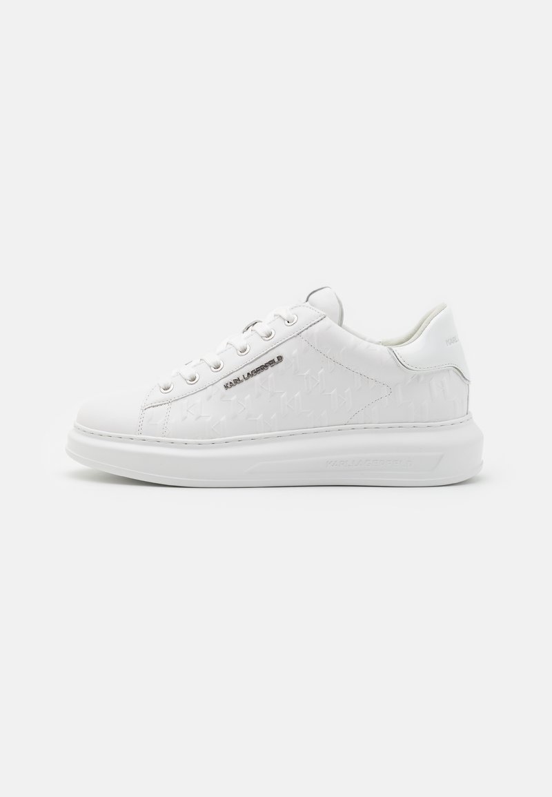 Hvite sneakers laget av glatt skinn med preget mønster. Har rund tå, snøring foran og strukturert såle. Sølv logo detalj på siden.