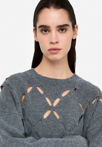 Maglione grigio lavorato a maglia con motivi a spirale, scollatura rotonda e maniche lunghe con dettagli sulle spalle e sulla schiena. Tessuto morbido.