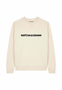 Sweatshirt beige avec un col en V, des manches raglan et un texte noir "MATCHA & DRAMA" sur la poitrine. Tissu doux et poignets côtelés.