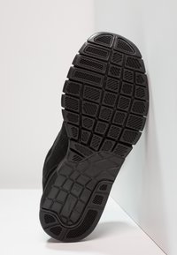 Semelle de chaussure de sport noire en caoutchouc texturé, avec plusieurs rainures pour la traction et un bord lisse, conçue pour une meilleure adhérence et durabilité.