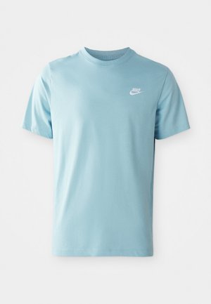 Svetlo modra kratko rokavna majica Nike s krožnim izrezom in belim logotipom Nike na levem prsnem delu, postavljena na preprosti beli ozadju.