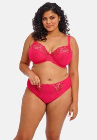 Ensemble de lingerie rose comprenant un soutien-gorge avec des bordures en dentelle florale et des bonnets rembourrés, associé à des culottes hipster assorties, toutes deux avec des détails en transparence.