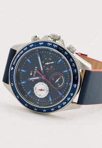 Orologio da polso da uomo con quadrante blu, lunetta tachimetro, tre sottodial, cassa argentata e cinturino in pelle blu con bordi rossi.