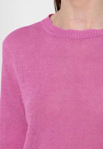 Maglione rosa a maglia con scollo rotondo. Il tessuto ha una fine texture e delicati motivi a coste. Inquadratura ravvicinata della parte superiore del corpo.