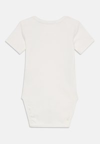 Bodysuit pour bébé à manches courtes en coton blanc, avec un col rond, des fermetures à pression au bas et une texture douce.