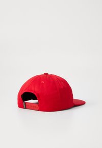 Punane pesapalli kork, millel on lame tipp, reguleeritav snapback sulgemine ja tekstuuriga kangas. Omab silmapaistvat õmblusmustrit kroonil.