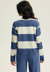Niebiesko-biały, paskowany, długi rękaw bluzka z okrągłym dekoltem, wykonana z miękkiego materiału, o luźnym kroju i opadających ramionach.