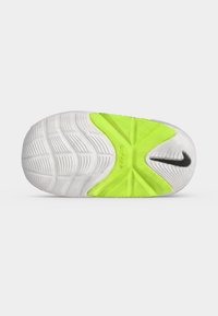 Σόλα λευκού και νέον πράσινου παπουτσιού Nike με υφή λαβής και μαύρο σήμα Nike κοντά στη φτέρνα.