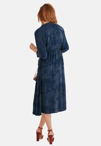 Robe midi à motif floral marine avec une couture à la taille et des manches longues ; présente un tissu texturé et une silhouette fluide.