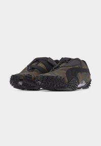 Low-profile camo sneakers with black textured soles, black side stripe, and dual black straps across the top.
