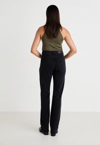 Zwarte high-waisted jeans met een rechte pijp, voorzien van twee achterzakken en een riemlus. De stof heeft een stevige denimtextuur.
