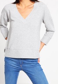 Grauer Pullover aus Baumwollmischung mit V-Ausschnitt, 3/4-Ärmeln und gerippter Textur. Verfügt über eine lockere Passform und seitliche Schlitze am Saum.