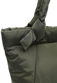 Vihreä pehmustettu kassi, jolla on jämäkkä muoto. Varustettu solmittulla hihnalla ja pehmeällä, sileällä pinnalla. Sopii rentoon käyttöön.