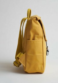 Zaino in tela gialla con una forma strutturata, dotato di una tasca laterale, spallacci regolabili e chiusura a patta ripiegabile.