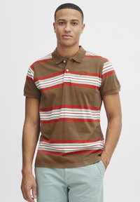 Brun polo-shirt med vandrette røde, hvide og blå striber. Har krave, to knapper og broderet logo på brystet.