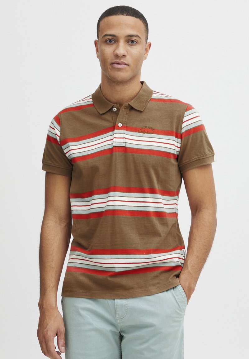 Brun polo-shirt med vandrette røde, hvide og blå striber. Har krave, to knapper og broderet logo på brystet.