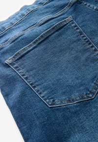 Tesatura din denim de culoare albastră închisă, având un buzunar la spate. Textura este netedă, cu cusături vizibile într-o nuanță portocalie contrastantă.