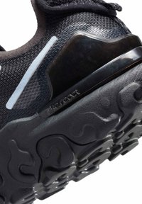 Primer plano de la suela de zapato Nike React negra con amortiguación texturizada y parte superior de tela con una banda reflectante.