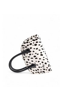 Biała torba z czarnymi kropkami, wykonana z teksturowanej tkaniny, z czarnymi skórzanymi uchwytami i zaokrąglonym kształtem dla łatwego noszenia.
