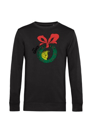 Black sweatshirt featuring a green wreath graphic with a yellow creature and red bow, accented with red berries. Long sleeves and crew neck design.