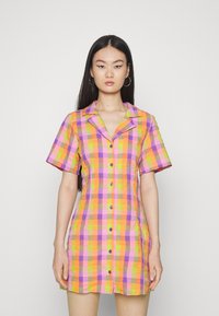 Vestido de manga curta, em padrão xadrez, nas vibrantes cores laranja, rosa e amarelo. Apresenta colarinho e botões frontais, tecido leve e um corte ajustado.