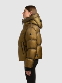 Olívazöld, fényes anyagú puffert kabát kapucnival és túlméretezett sziluettel. Cipzáras záródás, elasztikus mandzsetták és logó díszítések jellemzik.
