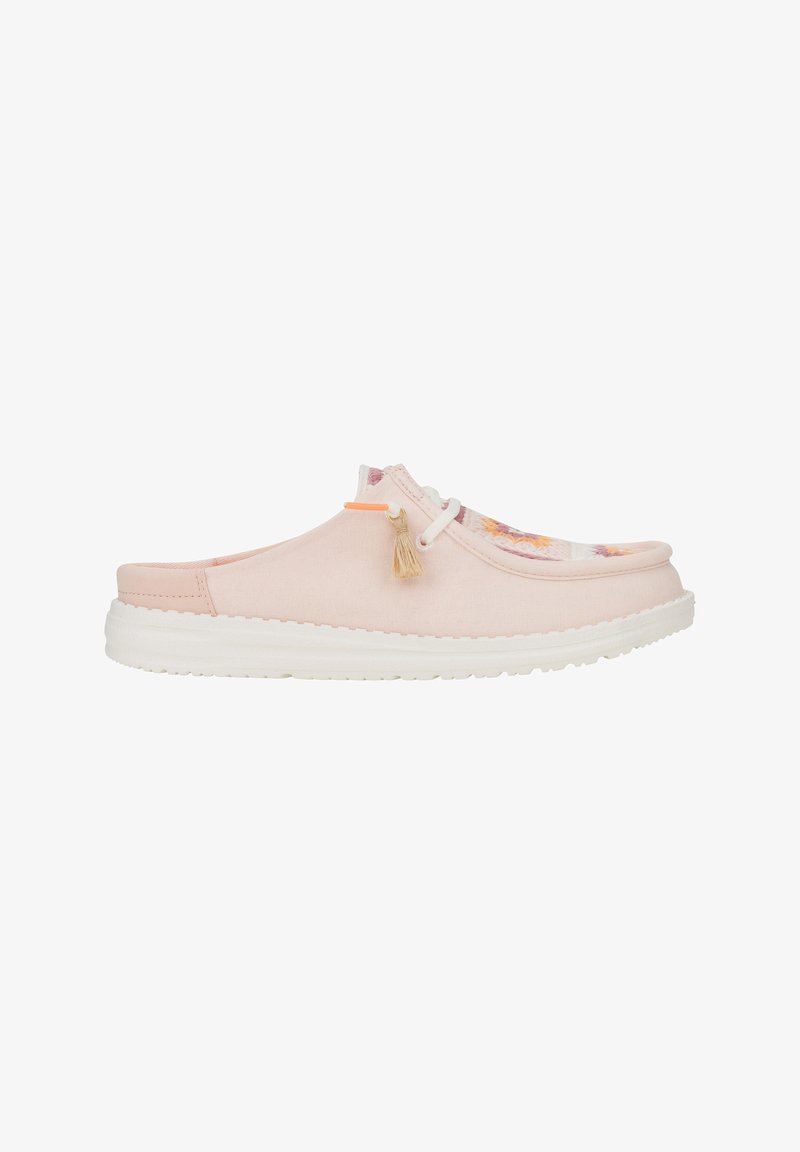 Zapato slip-on de lona rosa claro con suela de goma blanca, con acentos de diseño floral y un borlón decorativo en la parte superior.