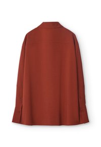 Lös passande tröja i rostfärg med krage, långa ärmar och knappade manschetter. Har ett texturerat tyg och en rak fåll.