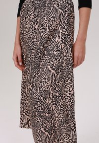 Jupe rose avec des motifs d'animaux noirs, en tissu doux, au design fluide et avec une taille plissée.