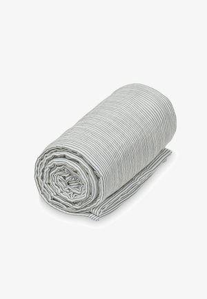 Fehér anyagtekercs vékony fekete vízszintes csíkokkal, gondosan feltekerve egy fehér felületen.