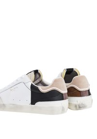 Vita och svarta sneakers med blandade material, inklusive slät läder och mocka. Accentuerade med beige, bruna och grå inslag.
