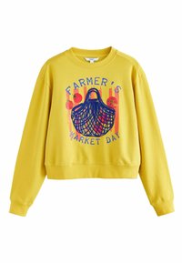 Gele trui met ronde hals, met een afbeelding van een markmand en fruit. Het ontwerp bevat blauwe tekst en kleurrijke accenten.