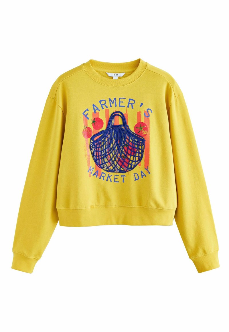 Gele trui met ronde hals, met een afbeelding van een markmand en fruit. Het ontwerp bevat blauwe tekst en kleurrijke accenten.