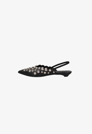 Chaussure plate slingback noire pointue avec clous boule argentés et petit talon sur fond blanc.