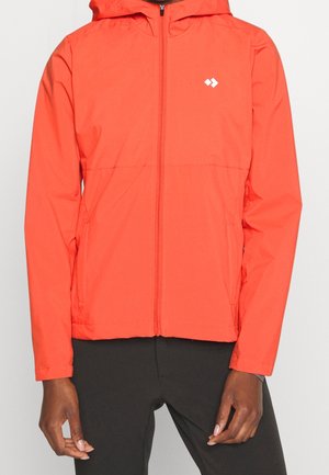 Veste à capuche orange vif avec fermeture éclair devant portée par une personne à la peau foncée et pantalon noir, logo sur la poitrine gauche.