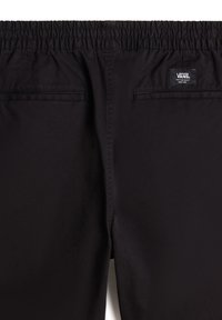 Pantaloni neri con cintura elastica, dotati di due tasche posteriori e etichetta Vans. Il tessuto sembra liscio con una finitura opaca e dettagli di cucitura minimi.