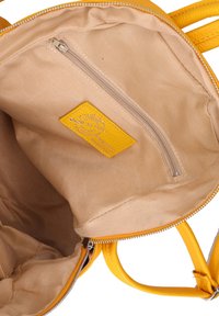 Interno di una borsa in pelle gialla con una fodera in tessuto beige, dotato di una tasca con zip e un'etichetta in pelle gialla con la dicitura "Made in Italy."
