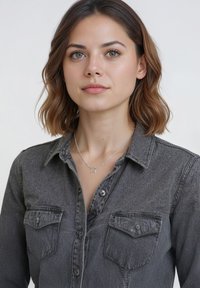 Grå denimskjorta med knäppning, två bröstfickor och krage. Bärs med ett silvrigt stjärnformat hängsmycke.