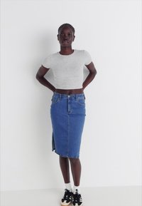 Pelēka saīsināta T-kreklu kombinācijā ar zilu denima zīda svārku ar sānu šķēlumu, papildināts ar melnbaltām sporta apaviem.