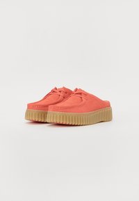Bottines en suede corail à enfiler, avec un bout rond et une tige rembourrée, dotées d'une semelle en caoutchouc épaisse et texturée dans une couleur tan contrastante.