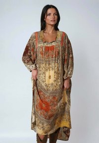 Robe bohème longue en orange, or et crème avec des motifs floraux délicats, des manches larges et un décolleté à cordon. Tissu doux et fluide.