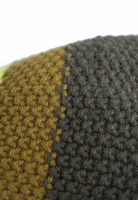 Knitted fabric with a textured surface featuring olive green, brown, and black sections, separated by a subtle stitching detail.