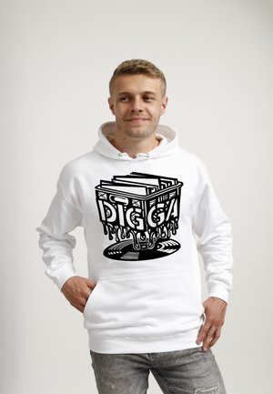 Ung mand iført en hvid hættetrøje med sort grafik af en dryppende kasse fyldt med vinylplader og ordet "DIGGA" foran, står med hænderne på hofterne.