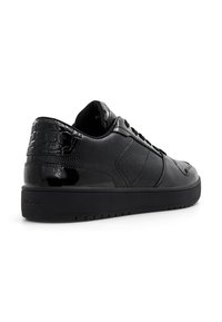 Black sneaker with glossy finish, textured details, and a patterned back. Features lace-up design and a rubber sole for grip.