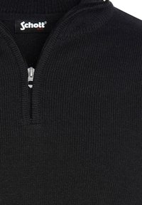 Schwarzer gerippter Strickpullover mit einem halben Reißverschluss. Hat einen erhöhten Kragen und ein gesticktes Logoetikett am Ausschnitt. Weiche Textur.