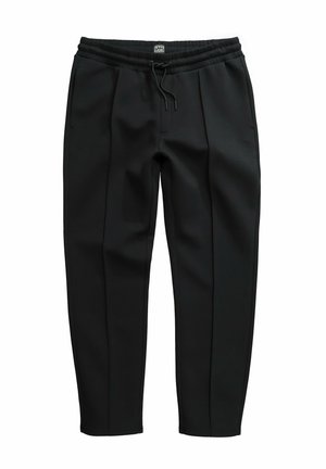 Schwarze elastische Hose mit vorderen Falten, seitlichen Taschen und einem Kordelzug, mit einem kleinen Markenetikett in der Mitte des Bunds.