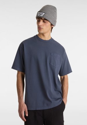 Granatowa bawełniana koszulka z krótkim rękawem, okrągłym dekoltem i kieszonką z przodu. Model nosi szary, żeberkowy beanie z naszywką z logo.