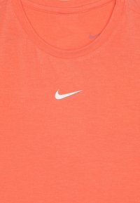 Koralli urheilupaita, joka on valmistettu pehmeästä, kevyestä kankaasta. Siinä on klassinen pyöreä kaula-aukko ja valkoinen Nike-logo keskellä.